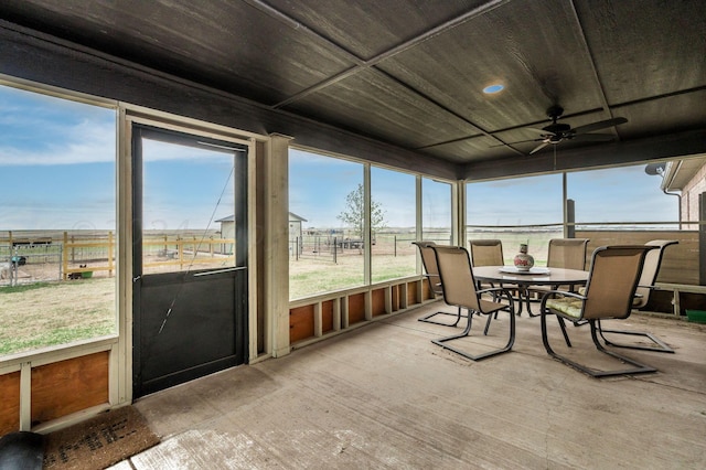 sunroom with ceiling fan and a rural view