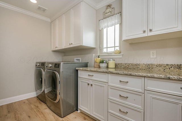 laundry area featuring cabinets, light hardwood / wood-style floors, crown molding, and washing machine and clothes dryer