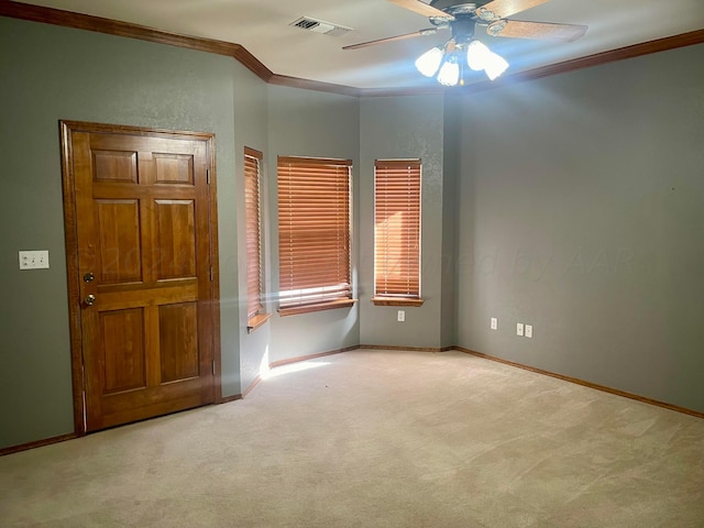 empty room featuring ceiling fan, light colored carpet, and crown molding