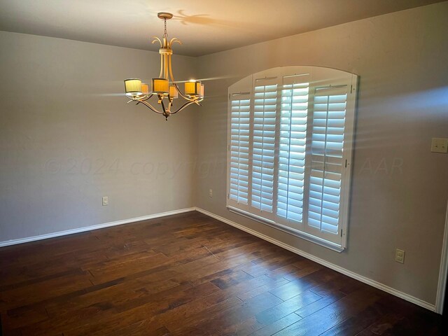 unfurnished room with dark hardwood / wood-style floors and an inviting chandelier