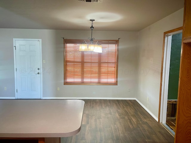 unfurnished dining area with an inviting chandelier and dark wood-type flooring