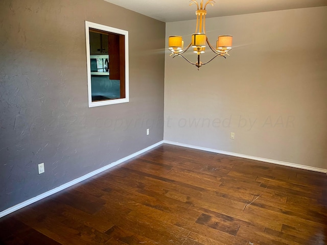 empty room with a notable chandelier and dark hardwood / wood-style flooring