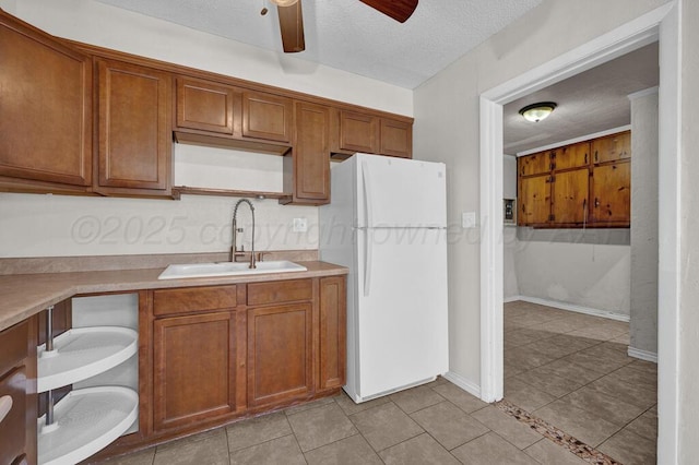 kitchen with sink, light tile patterned floors, ceiling fan, a textured ceiling, and white fridge