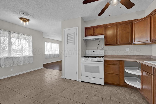 kitchen featuring ceiling fan, white gas range, light tile patterned flooring, and a textured ceiling