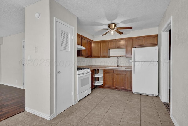 kitchen with sink, light tile patterned floors, white appliances, ceiling fan, and a textured ceiling