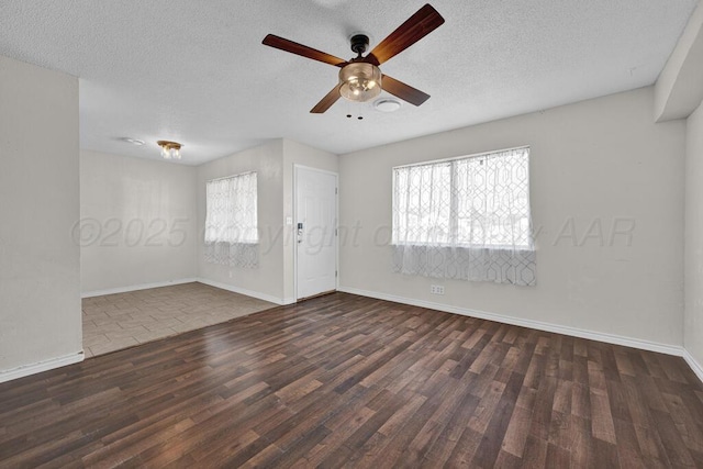 spare room featuring dark hardwood / wood-style flooring, ceiling fan, a wealth of natural light, and a textured ceiling