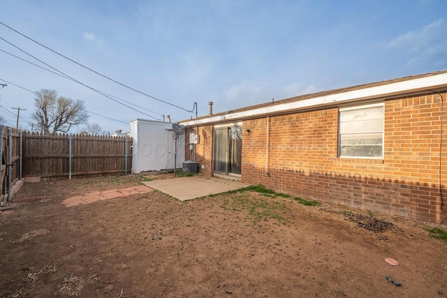 back of property with brick siding, a shed, an outdoor structure, a fenced backyard, and a patio