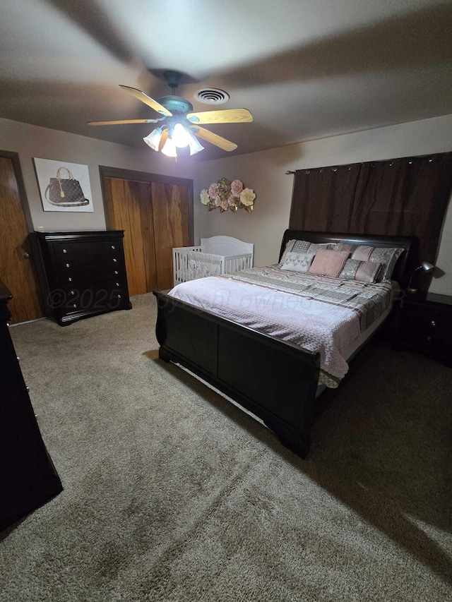 bedroom with a closet, carpet floors, visible vents, and ceiling fan