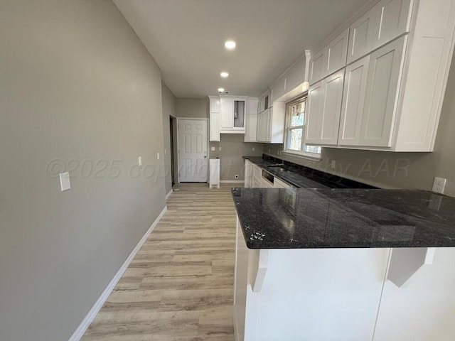 kitchen with dark stone counters, a peninsula, light wood-style floors, white cabinets, and recessed lighting