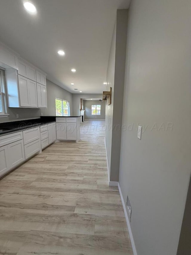1606 S Hughes St, Amarillo, TX 79102 - kitchen with recessed lighting, a peninsula, dark countertops, white cabinetry, and light wood-type flooring