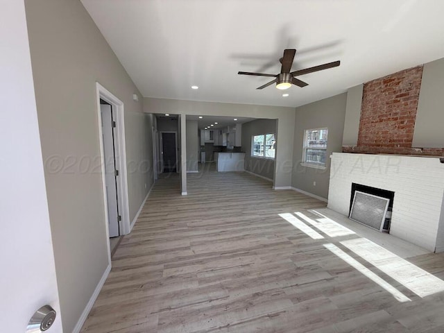 unfurnished living room featuring ceiling fan, a fireplace, light wood-style flooring, baseboards, and recessed lighting
