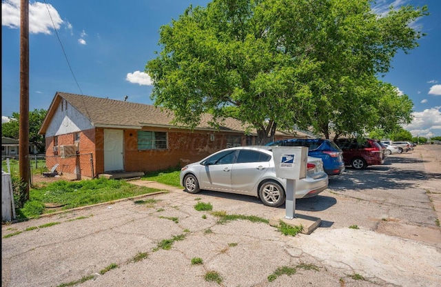 view of front of home featuring uncovered parking, brick siding, and fence