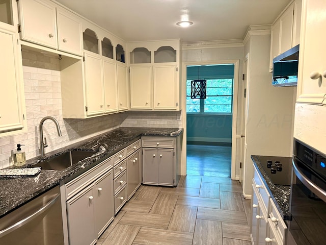 kitchen featuring stainless steel dishwasher, a sink, dark stone countertops, backsplash, and oven
