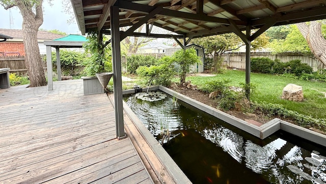 dock area with a wooden deck, a garden pond, a gazebo, a fenced backyard, and a yard