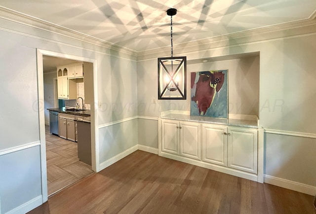 unfurnished dining area with baseboards, ornamental molding, a sink, and dark wood-type flooring