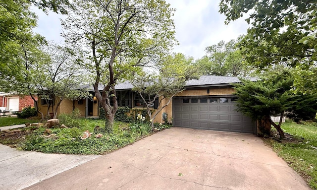 single story home with concrete driveway, roof with shingles, brick siding, and an attached garage