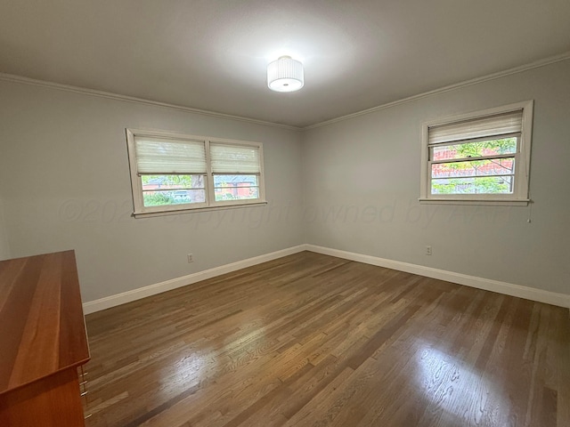 unfurnished room featuring a healthy amount of sunlight, dark wood finished floors, and crown molding