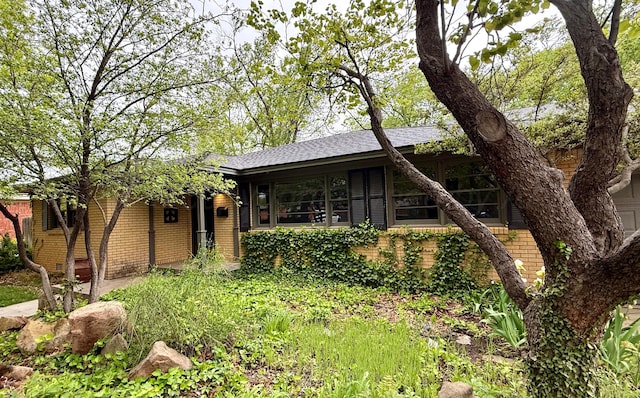 view of front of home with roof with shingles and brick siding