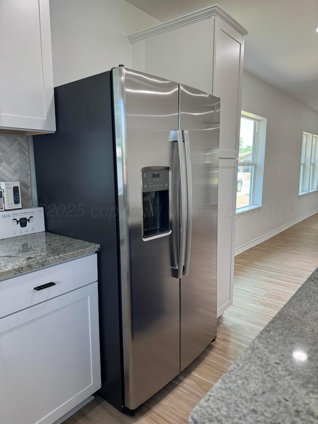 kitchen featuring stone counters, white cabinets, backsplash, and stainless steel fridge with ice dispenser