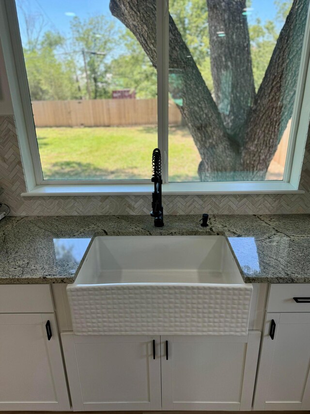 room details with light stone counters, sink, and white cabinets