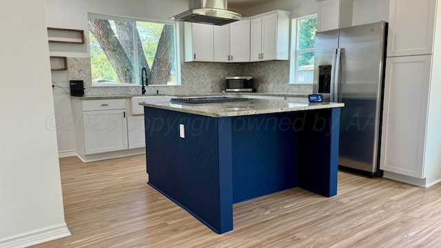 kitchen featuring appliances with stainless steel finishes, a center island, light stone countertops, and white cabinets