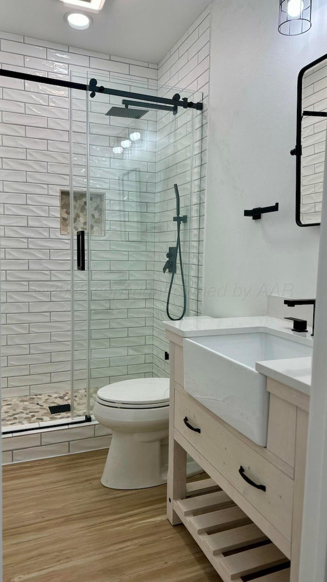 bathroom featuring hardwood / wood-style flooring, vanity, toilet, and an enclosed shower