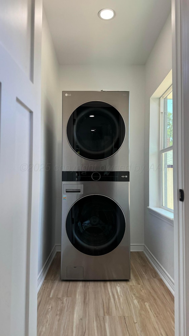 clothes washing area featuring stacked washer / drying machine and light hardwood / wood-style flooring