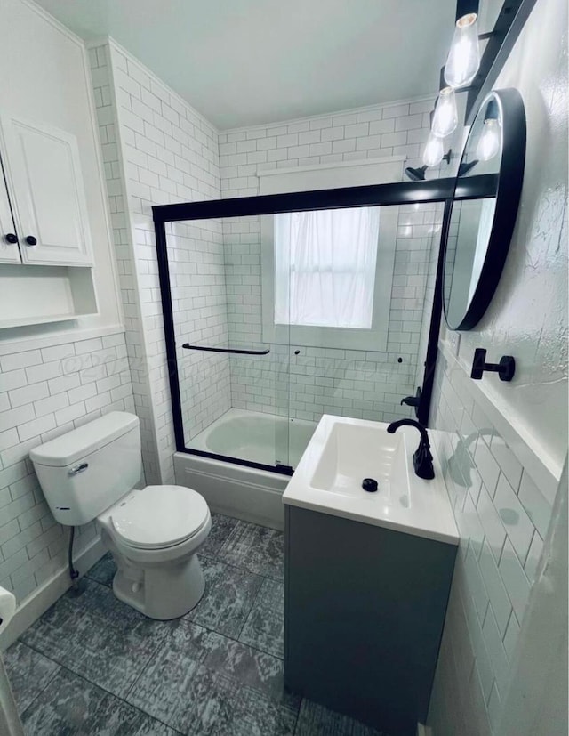 full bath with combined bath / shower with glass door, tile walls, vanity, and toilet