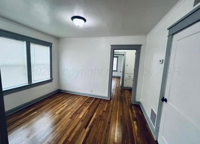 spare room featuring crown molding, baseboards, visible vents, and dark wood-style floors
