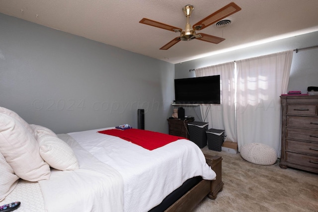 bedroom with ceiling fan, light carpet, and a textured ceiling