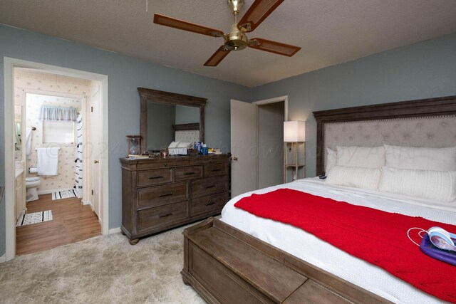 bedroom with ceiling fan, light colored carpet, connected bathroom, and a textured ceiling