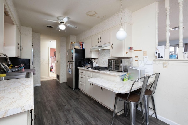 kitchen featuring tasteful backsplash, a breakfast bar, white cabinetry, hanging light fixtures, and stainless steel appliances