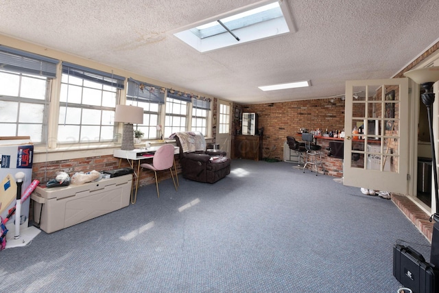 interior space with brick wall, carpet, a skylight, and a textured ceiling