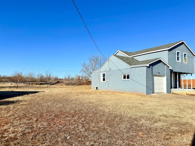 view of side of home featuring a garage, a yard, brick siding, and concrete driveway