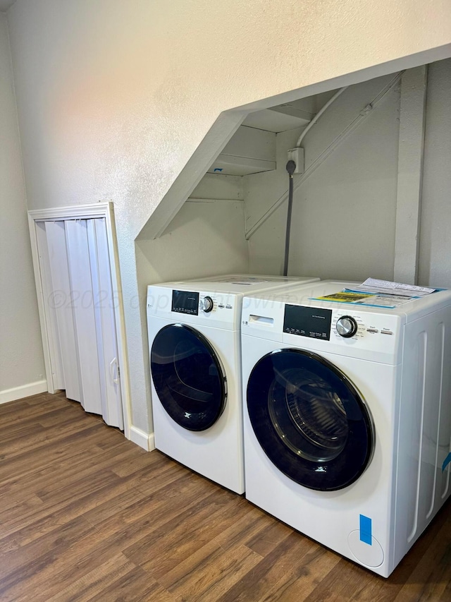 laundry area with laundry area, washer and clothes dryer, dark wood finished floors, and baseboards