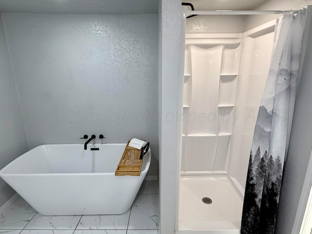 full bathroom with marble finish floor, a shower stall, and a freestanding bath