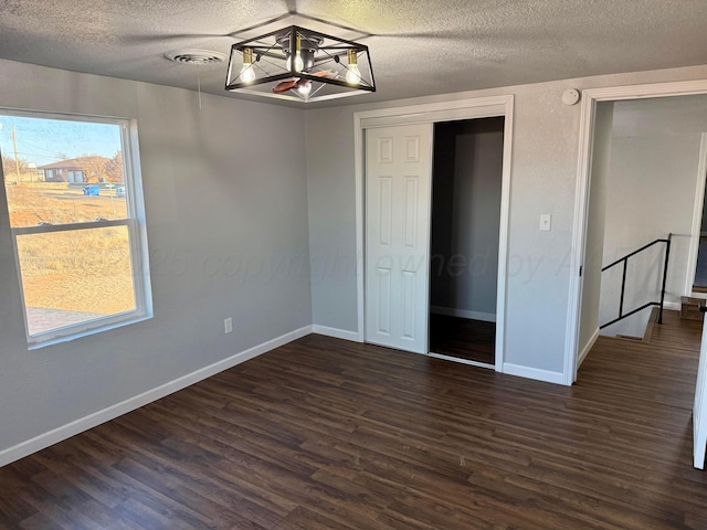 unfurnished bedroom featuring dark wood-style floors, baseboards, visible vents, and a textured ceiling