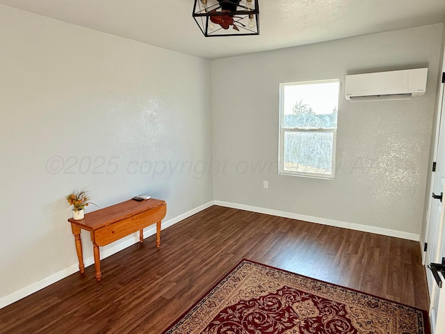 empty room featuring dark wood-style floors, a wall unit AC, and baseboards