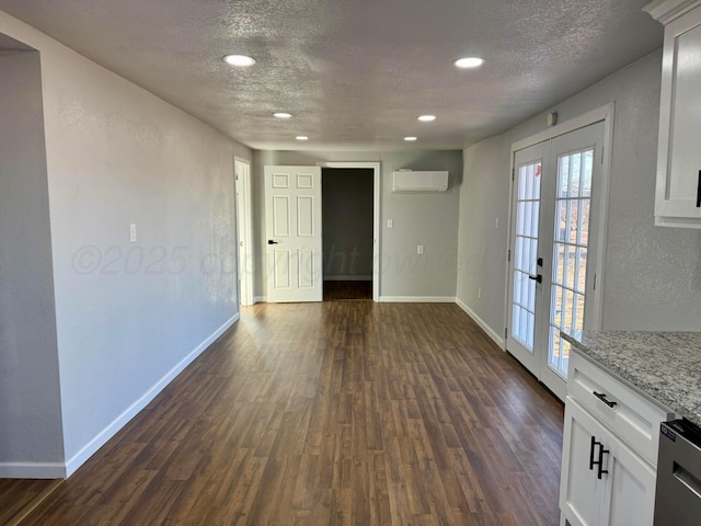 unfurnished room featuring a textured ceiling, french doors, a wall mounted AC, and dark wood finished floors