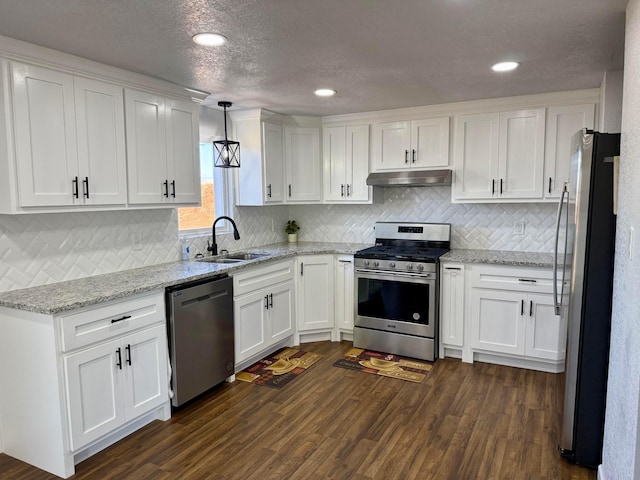 kitchen featuring decorative light fixtures, stainless steel appliances, under cabinet range hood, white cabinetry, and a sink