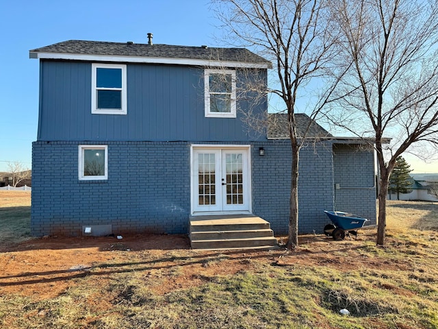 rear view of house featuring entry steps, brick siding, a yard, and french doors