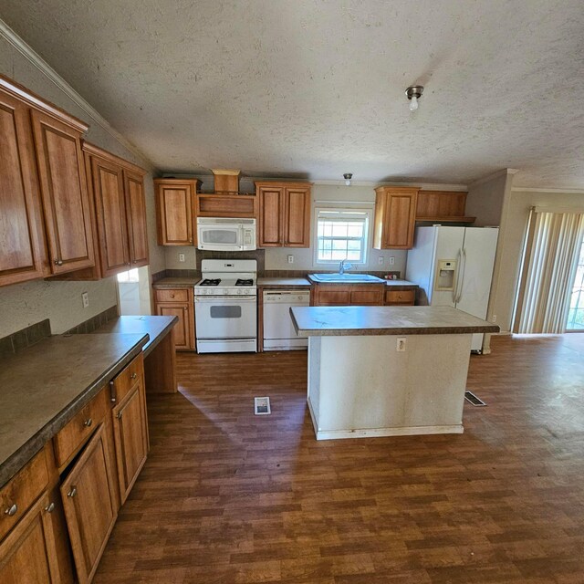 kitchen featuring sink, dark hardwood / wood-style floors, a textured ceiling, white appliances, and a kitchen island