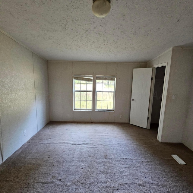 carpeted empty room with a textured ceiling