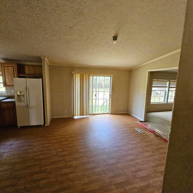 unfurnished living room with ornamental molding, a textured ceiling, a wealth of natural light, and dark wood-type flooring