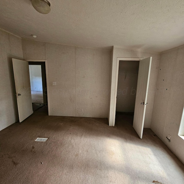 unfurnished bedroom with a textured ceiling and light colored carpet