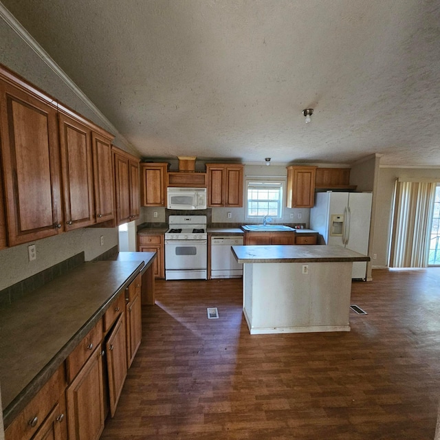 kitchen with a center island, white appliances, sink, dark hardwood / wood-style floors, and a textured ceiling