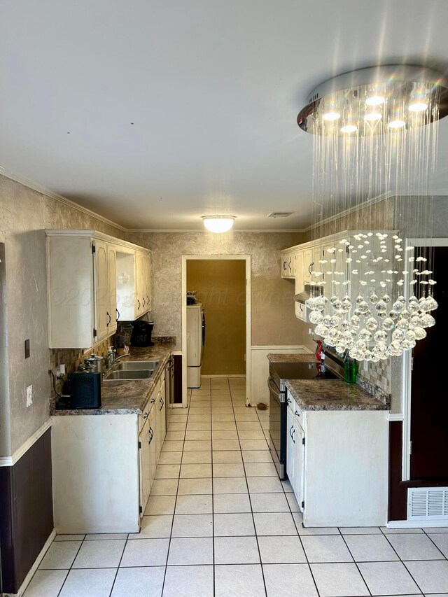 702 Floyd Ave, Dumas, TX 79029 - kitchen featuring stainless steel range with electric cooktop, a sink, light tile patterned floors, dark countertops, and washer / clothes dryer