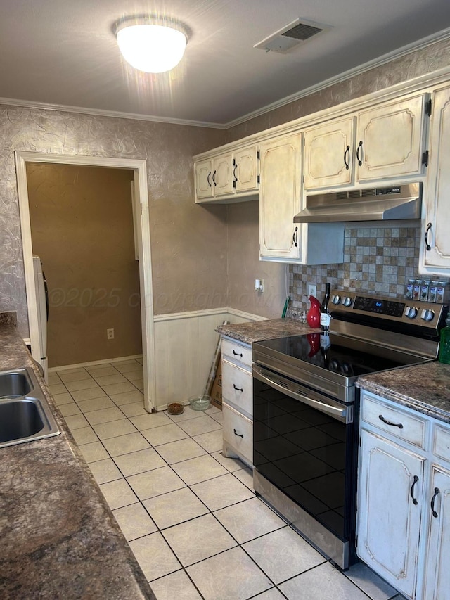 702 Floyd Ave, Dumas, TX 79029 - kitchen with electric range, under cabinet range hood, dark countertops, light tile patterned floors, and a sink