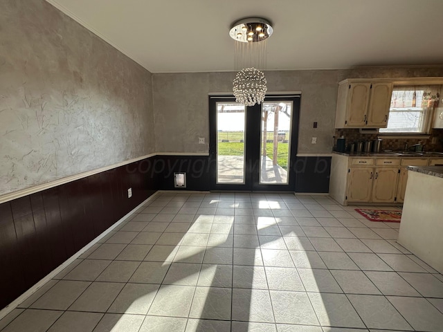 702 Floyd Ave, Dumas, TX 79029 - unfurnished dining area with a chandelier, light tile patterned flooring, and a wainscoted wall