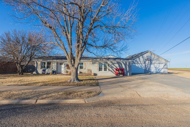 single story home featuring a garage, driveway, a front lawn, and solar panels